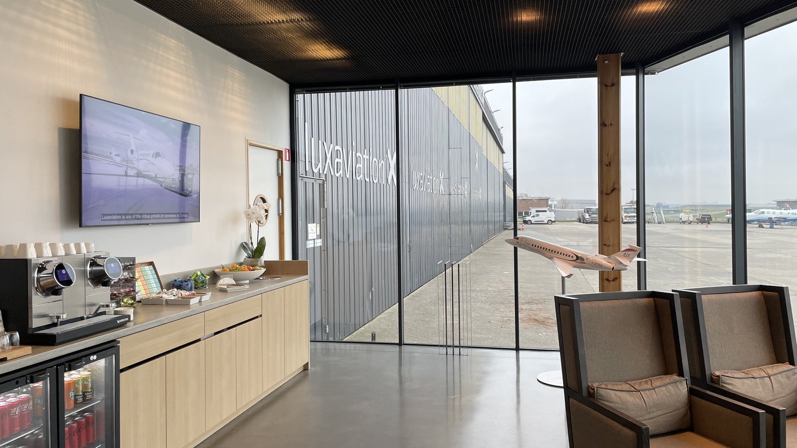 Lounge d'aviation privée avec écran et vue sur la piste